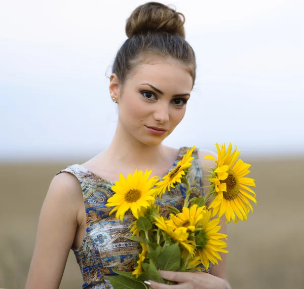 Young beautiful woman on blooming sunflower field in summer — Stock Photo, Image