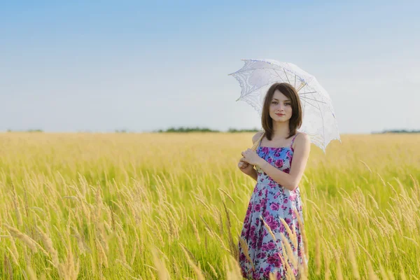 Schöne traurige und einsame Frau mit Regenschirm, die im Weizenfi wandelt — Stockfoto