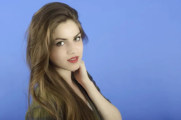 Studio portrait of beautiful woman with long hair on blue backgr — Stock Photo, Image