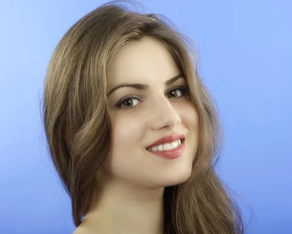 Studioporträt einer schönen Frau mit langen Haaren auf blauem Hintergrund — Stockfoto