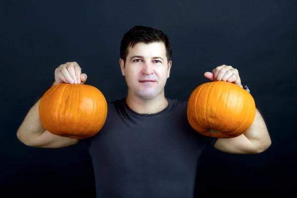 Homem mostra halloween abóboras isolado no fundo preto — Fotografia de Stock