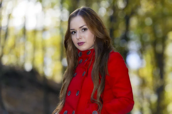 Beautiful elegant woman standing in a park in autumn — Stock Photo, Image