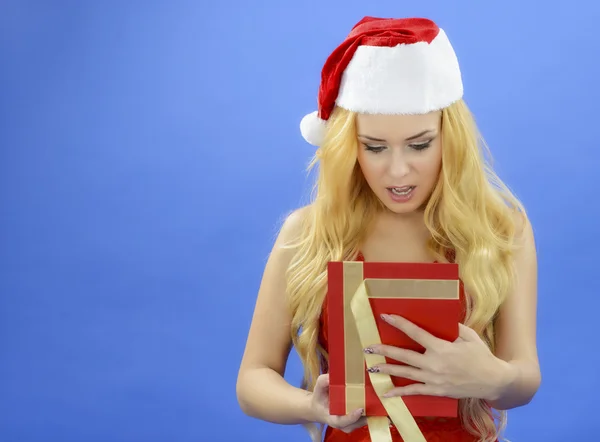 Mulher de Natal segurando presente usando chapéu de Pai Natal. Isolado em azul — Fotografia de Stock