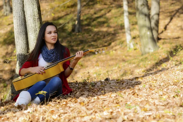 Krásná bruneta kytara hráč dívku v lese — Stock fotografie