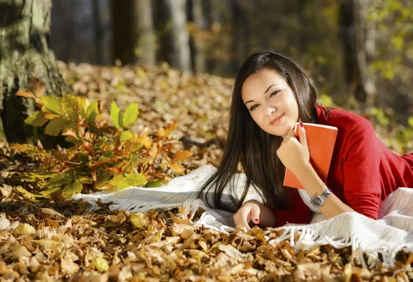 Menina bonita com livro no parque de outono — Fotografia de Stock