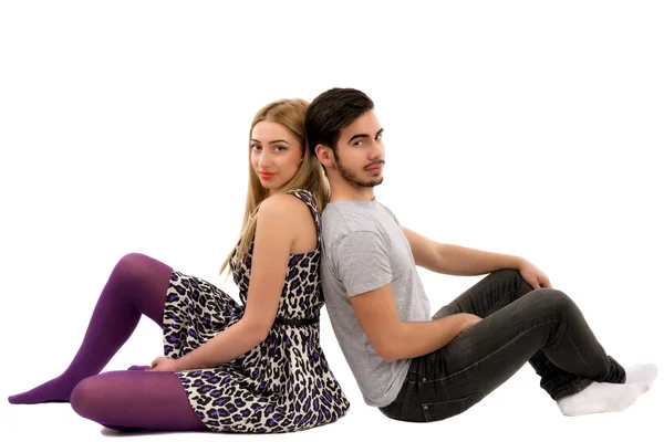 Cheerful young couple sitting with back to each other on floor, — Stock Photo, Image