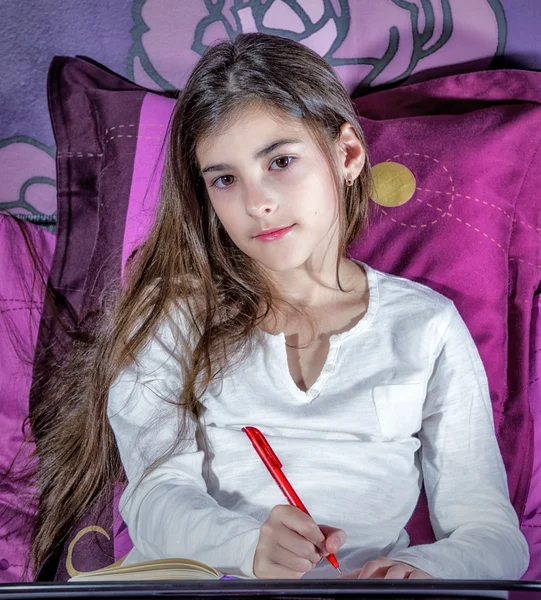 Cute dziewczynka pisania na notebook leżąc na łóżku — Zdjęcie stockowe