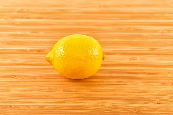 Yellow lemon sit on a worn butcher block cutting board — Stock Photo, Image