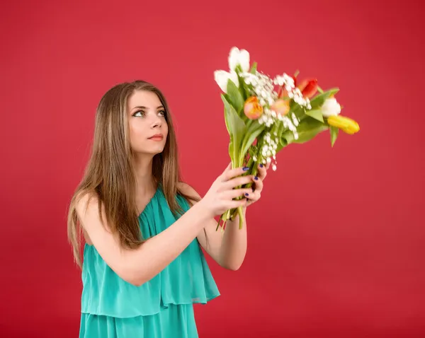 Menina bonita em um vestido de verão com tulipas em um fundo vermelho — Fotografia de Stock