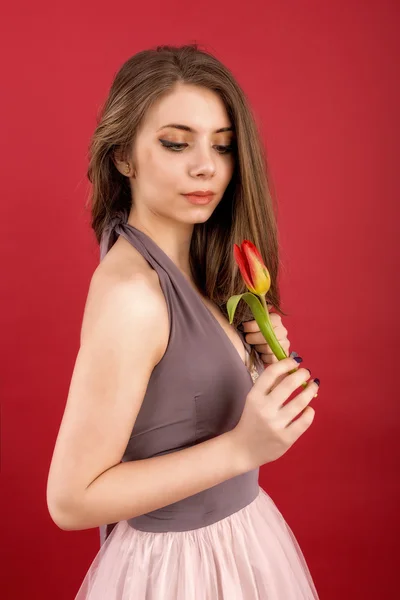 Tizenéves lány pózol, tulipán, kezében piros háttér — Stock Fotó