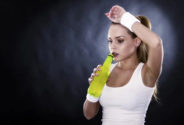 Studio portrait of a young beautiful sporty woman, holding a bot — Stock Photo, Image