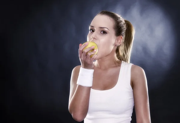 Sportovní žena ruce zralé žluté jablko, izolované na černém pozadí — Stock fotografie