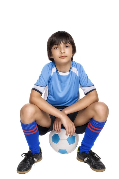 Boy in complete soccer outfit sitting on a football — Stock Photo, Image