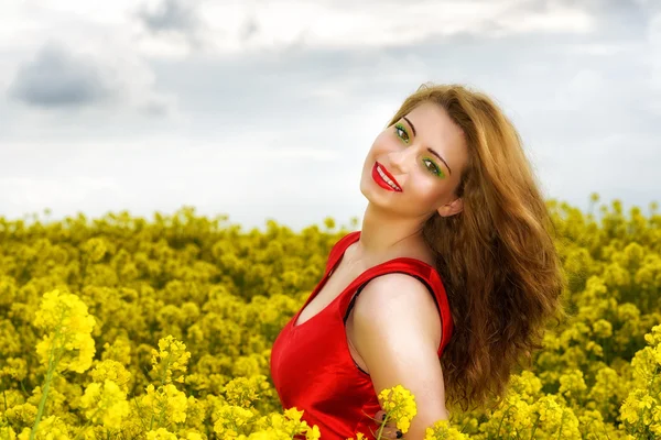 Beautiful young  woman in red dress in yellow field — Stock Photo, Image