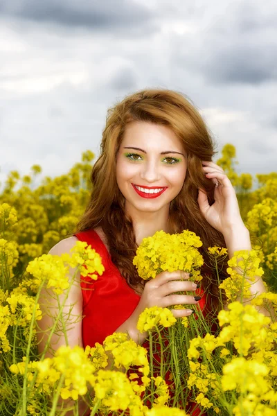 Hermosa joven en vestido rojo en el campo amarillo — Foto de Stock