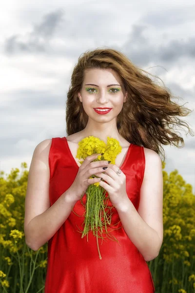 Όμορφη νεαρή γυναίκα με κόκκινο φόρεμα σε κίτρινο πεδίο — Φωτογραφία Αρχείου