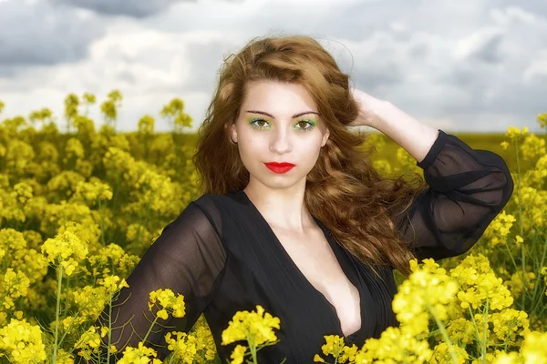 Belle jeune femme en robe noire dans le champ jaune — Photo