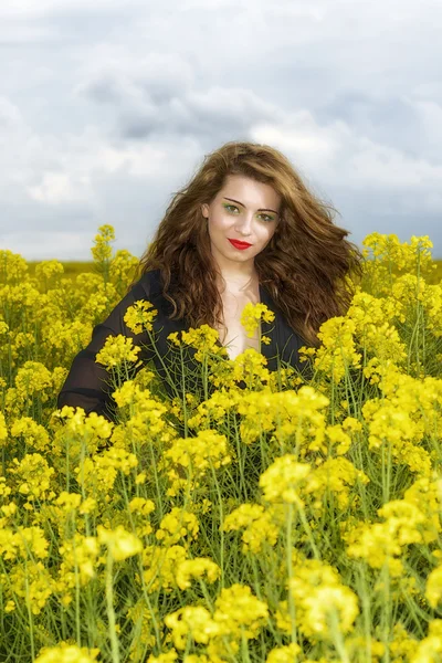 Beautiful young  woman in black dress in yellow field — Stock Photo, Image