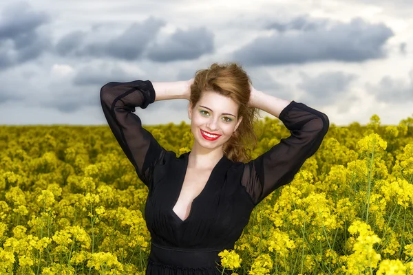 Beautiful young  woman in black dress in yellow field — Stock Photo, Image