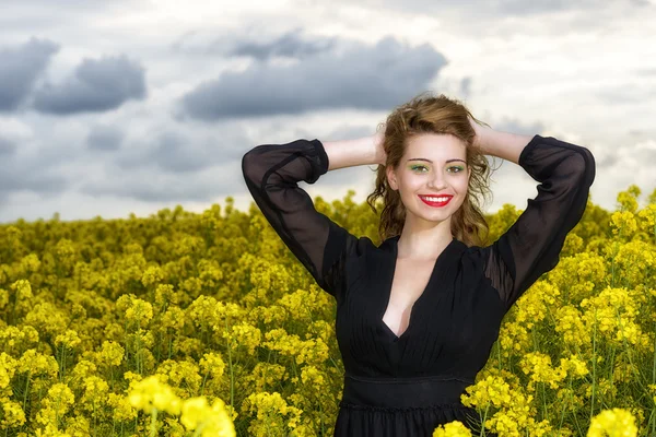 Hermosa joven en vestido negro en el campo amarillo — Foto de Stock