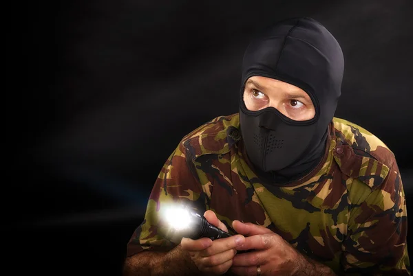 Soldat sur fond noir avec une lampe de poche en camouflage mi — Photo