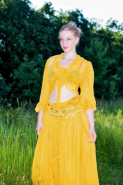 Hermosa mujer en vestido amarillo posando en la naturaleza — Foto de Stock