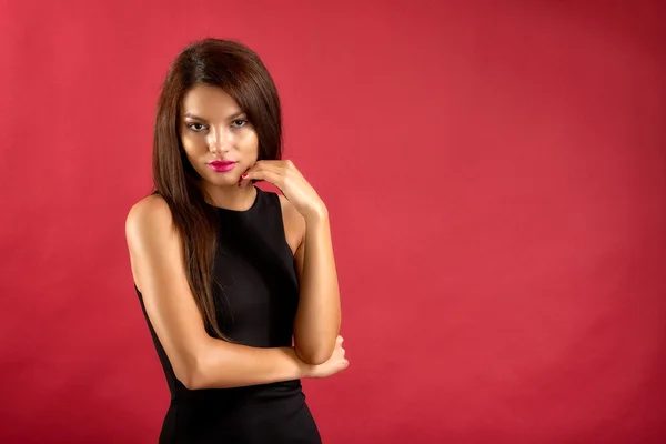 Sexy brunette woman in black dress isolated on red background — Stock Photo, Image
