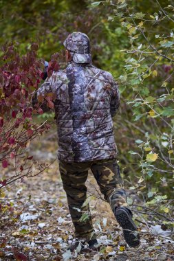 Kamuflaj giysileri içinde profesyonel fotoğrafçı doğada çalışıyor. sonbahar günü.