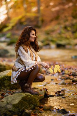 Sonbahar mevsiminde bir dağ nehrinin yanında farklı pozisyonlarda güzel bir kadınla sonbahar portresi..