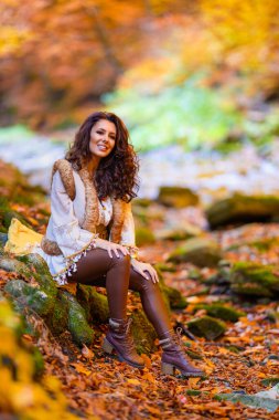 Sonbahar mevsiminde bir dağ nehrinin yanında farklı pozisyonlarda güzel bir kadınla sonbahar portresi..