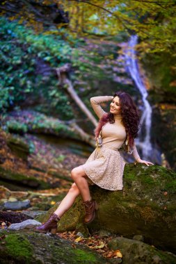 Şelalenin yanında oturan güzel bir kadın düşerken farklı pozisyonlarda.