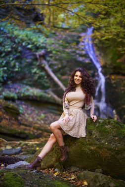 Şelalenin yanında oturan güzel bir kadın düşerken farklı pozisyonlarda.