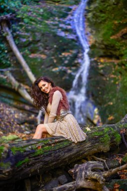 Şelalenin yanında oturan güzel bir kadın düşerken farklı pozisyonlarda.