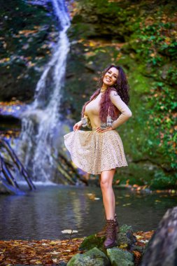 Şelalenin yanında oturan güzel bir kadın düşerken farklı pozisyonlarda.