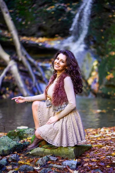 Piękna Kobieta Siedząca Przy Wodospadzie Różnych Pozycjach Podczas Jesieni — Zdjęcie stockowe
