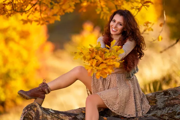 一个美丽的女人躺在一棵老树的圆木上 秋天的色彩 — 图库照片