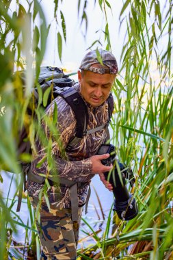 Kamuflaj kıyafetli profesyonel bir vahşi yaşam fotoğrafçısı.