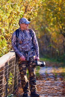 Kamuflaj kıyafetli profesyonel bir vahşi yaşam fotoğrafçısı.