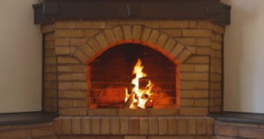 Tuğladan ev yapımı Noel şöminesinde ateş alevleri. Şöminenin üzerinde şenlik çelengi asılı..