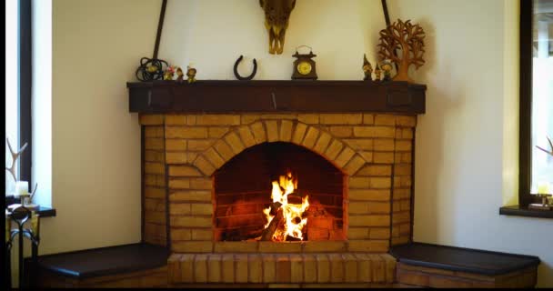 火の炎はレンガ造りの家庭クリスマス暖炉で燃える お祝いの花輪は暖炉の上に掛け — ストック動画
