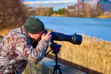 Kamuflaj kıyafetli profesyonel fotoğrafçı doğada gizlidir.
