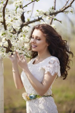 Baharda çiçek açan ağaçların yanında uzun saçlı güzel bir kadının portresi..