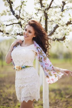 Baharda çiçek açan ağaçların yanında uzun saçlı güzel bir kadının portresi..