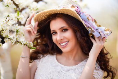 Baharda çiçek açan ağaçların yanında uzun saçlı güzel bir kadının portresi..