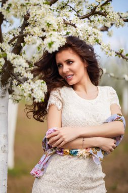 Baharda çiçek açan ağaçların yanında uzun saçlı güzel bir kadının portresi..