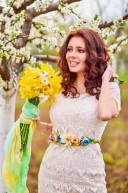 Baharda çiçek açan ağaçların yanında uzun saçlı güzel bir kadının portresi..