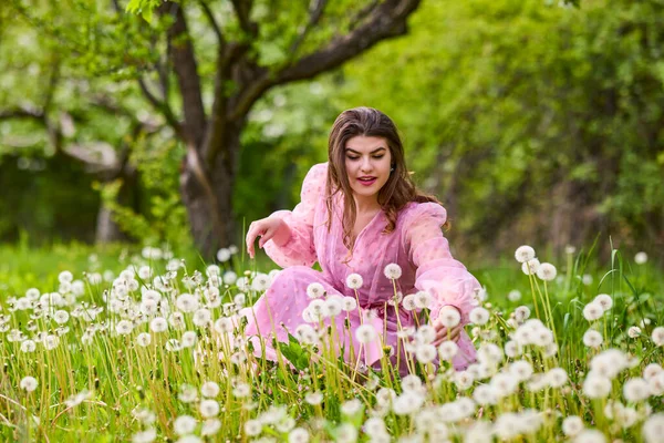 Pembe elbiseli genç bir kadın çiçek açan bir elmanın yanında poz veriyor, bahar portresi..