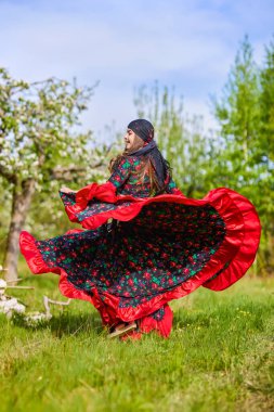 beautiful woman in traditional gypsy dress posing in nature in spring