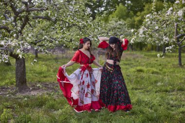 Geleneksel çingene elbiseli iki dansçı bahar günü doğada dans eder.