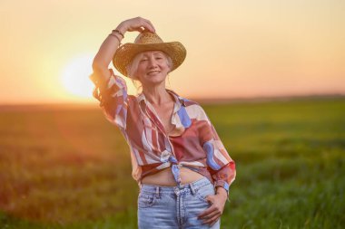 Gün batımında buğday tarlasında orta yaşlı bir kadının portresi.